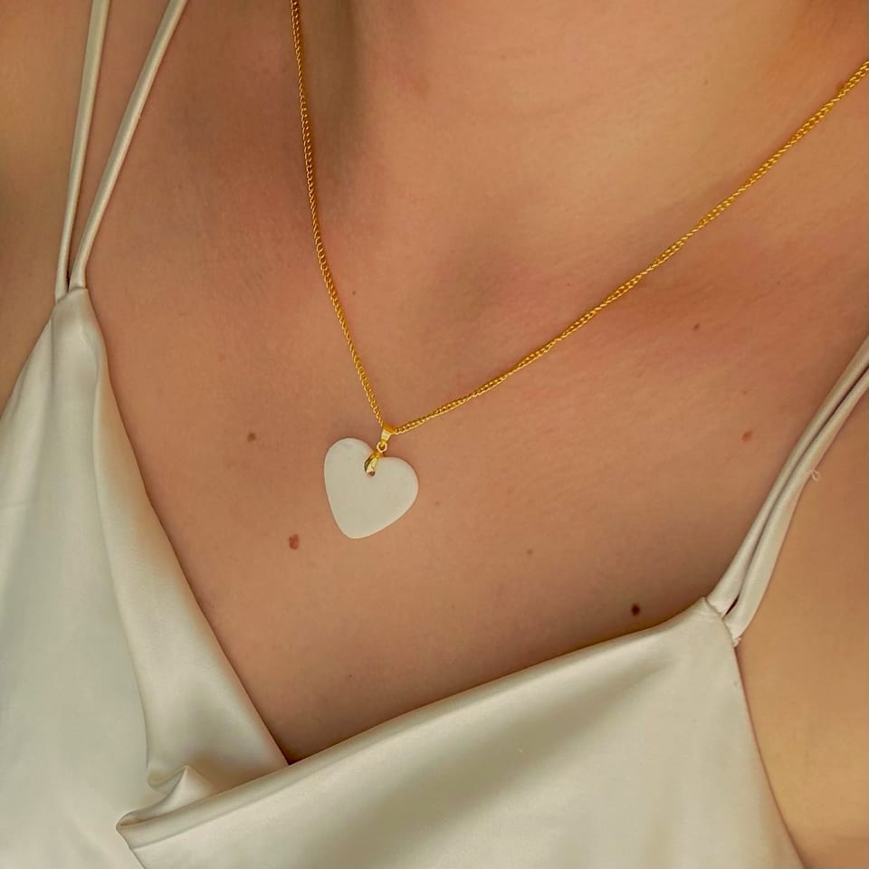 Slađana wearing a breast milk pendant necklace in warm light