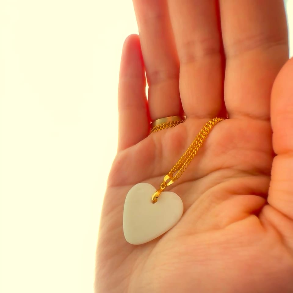 Hand holding a breast milk pendant necklace toward warm light
